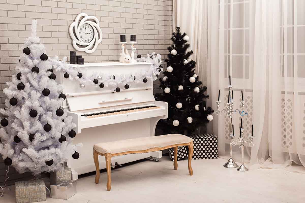 stanza con un pianoforte al centro e ai lati due alberi di Natale, uno di colore bianco e nero e l'altro verde con palline grigie