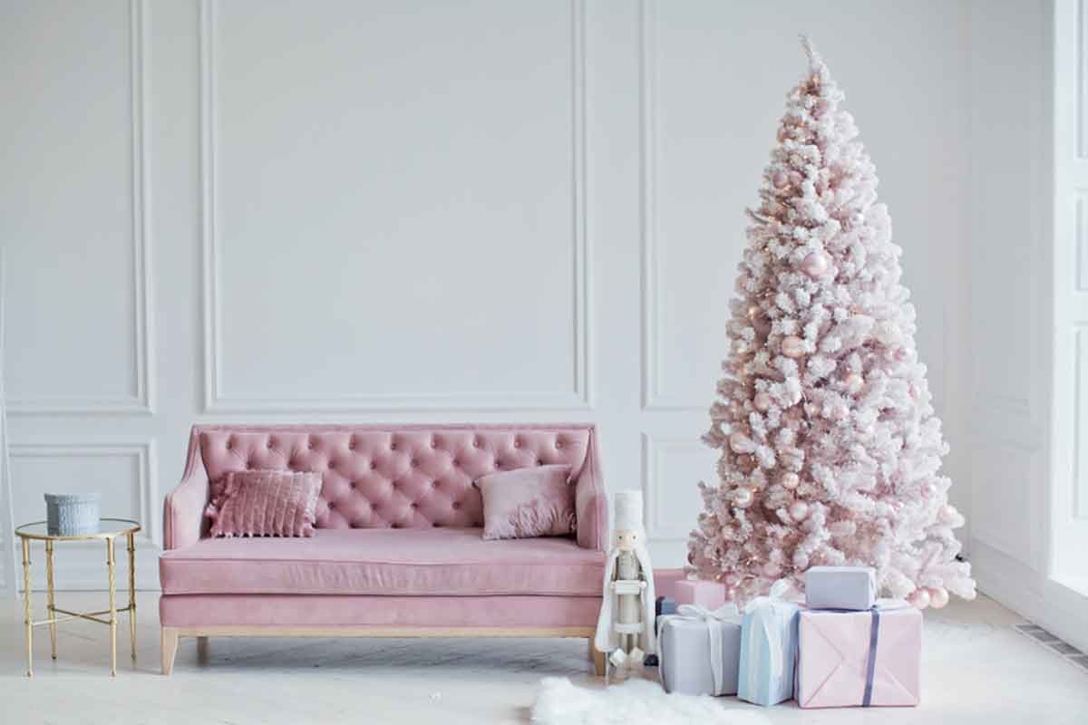 soggiorno con pareti bianche, divano rosa e albero di Natale abbinato con colori bianco e rosa