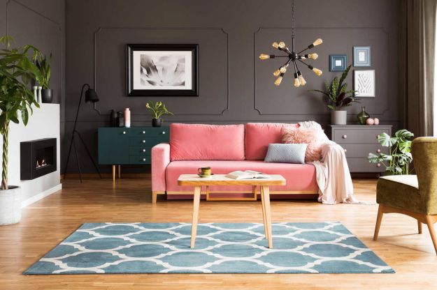 soggiorno con divano rosa, tappeto azzurro e pareti grigio scuro