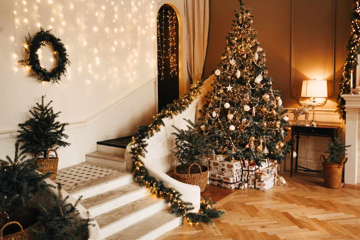 salotto con albero di natale con lucine calde e palline decorative, scale con arredamento natalizio, lucine e ghirlande
