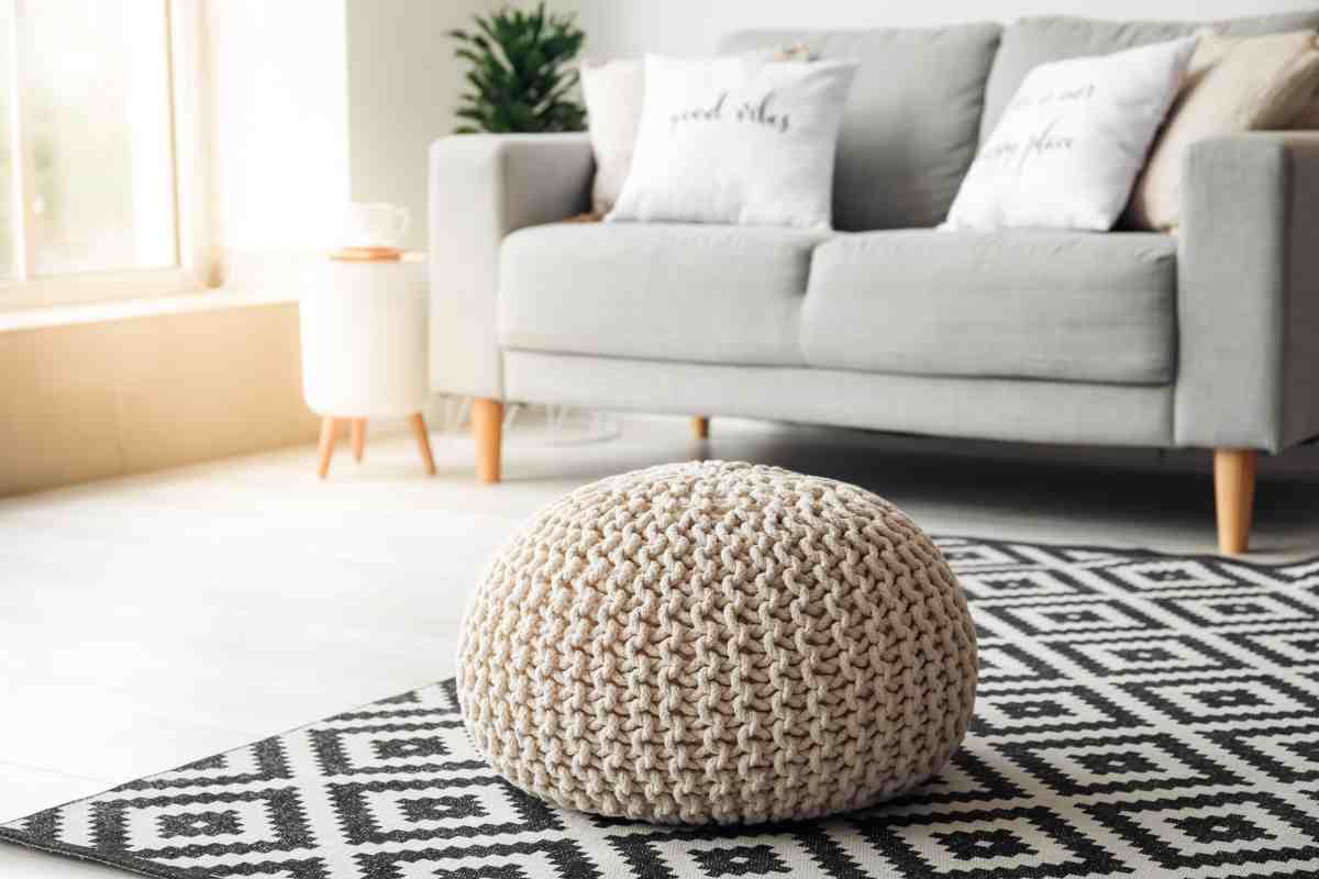 Soggiorno stile nordico con divano, tappeto e pouf in lana lavorata a mano