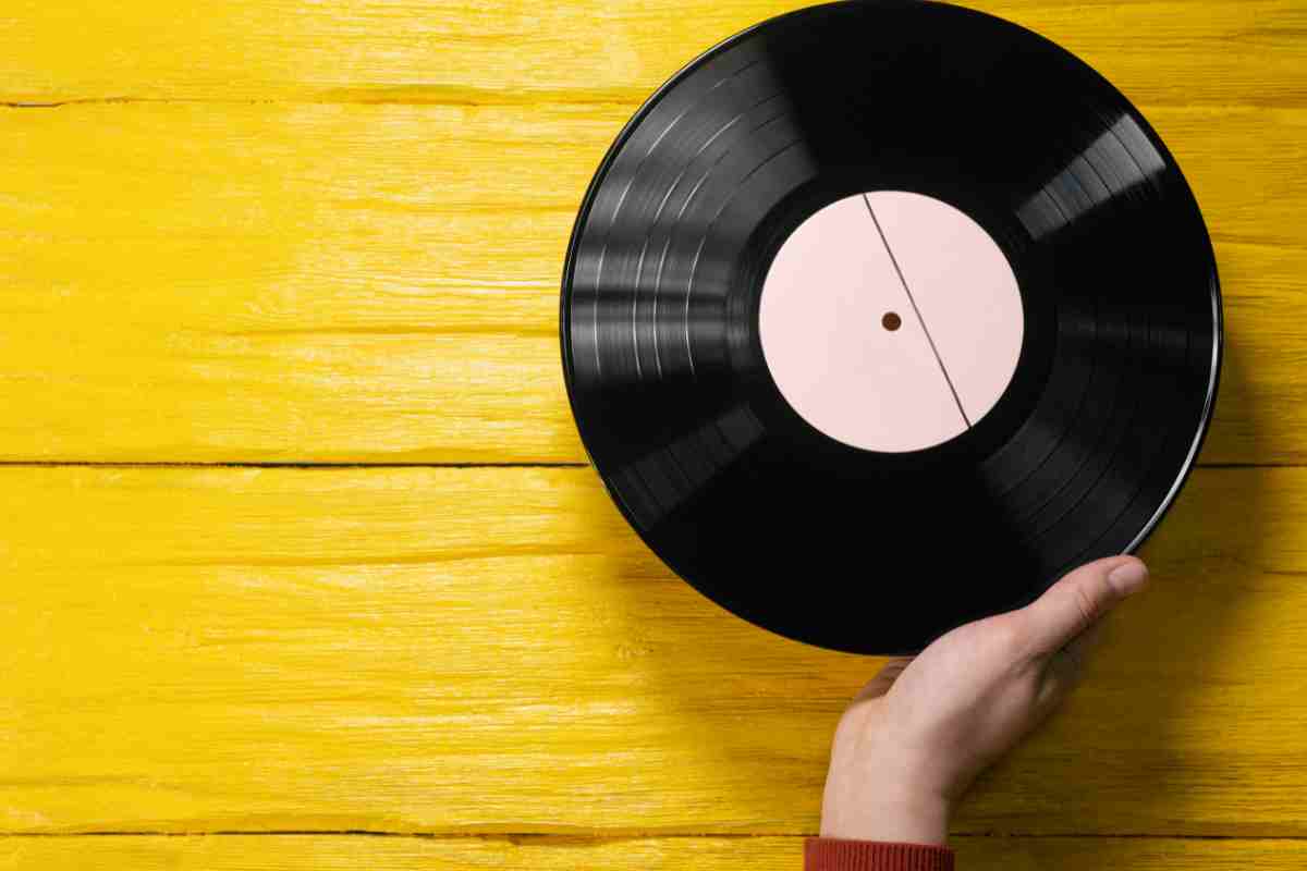 mano regge un disco in vinile