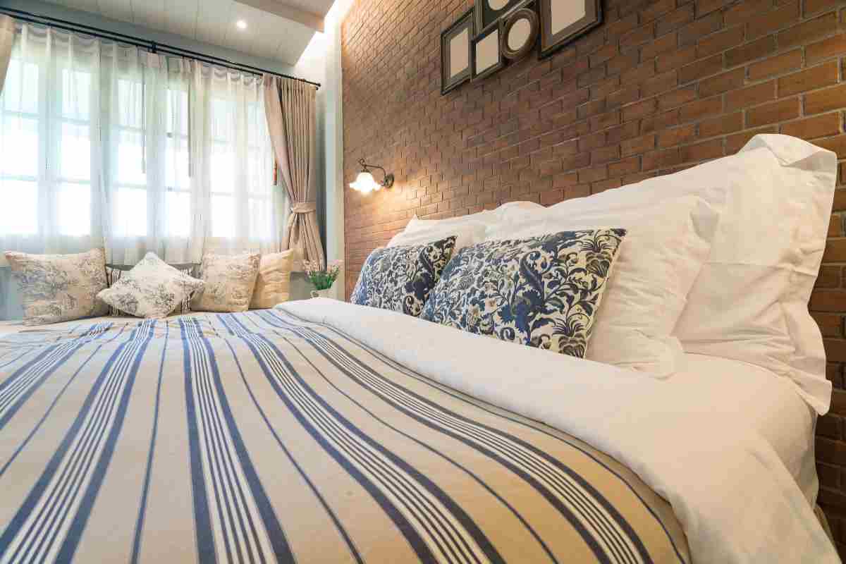 Camera da letto stile country chic con copriletto a righe e cuscini floreali
