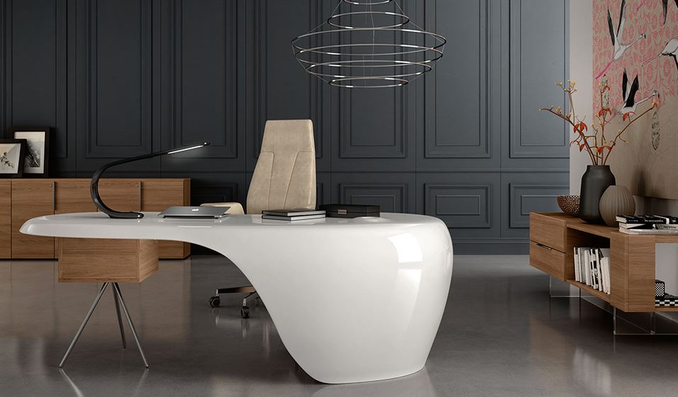 scrivania di design di colore bianco, con sopra lampada, computer e libri, con sedia da ufficio di colore beige, in stanza con parete sullo sfondo nero e due mobili in legno