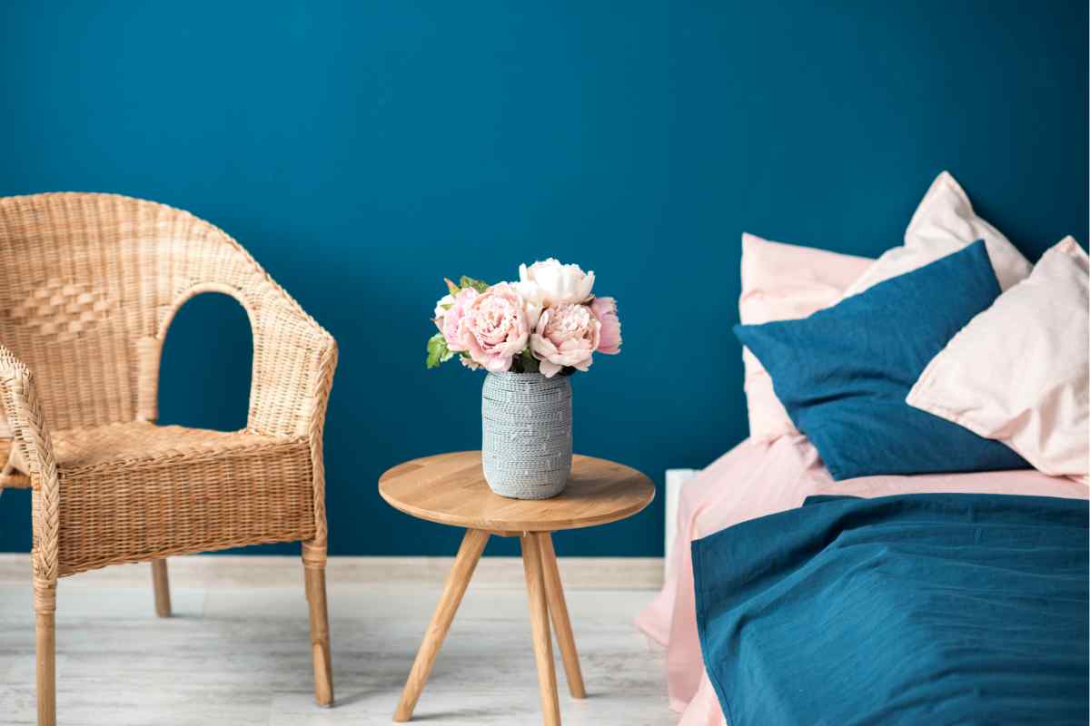 Camera letto vintage nei colori blu e rosa con poltroncina in rattan