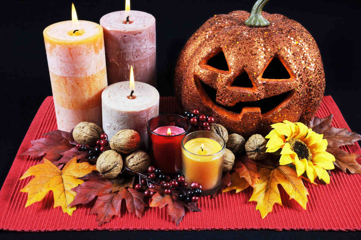 tipico centrotavola di halloween con candele zucca intagliata fiori e frutta secca