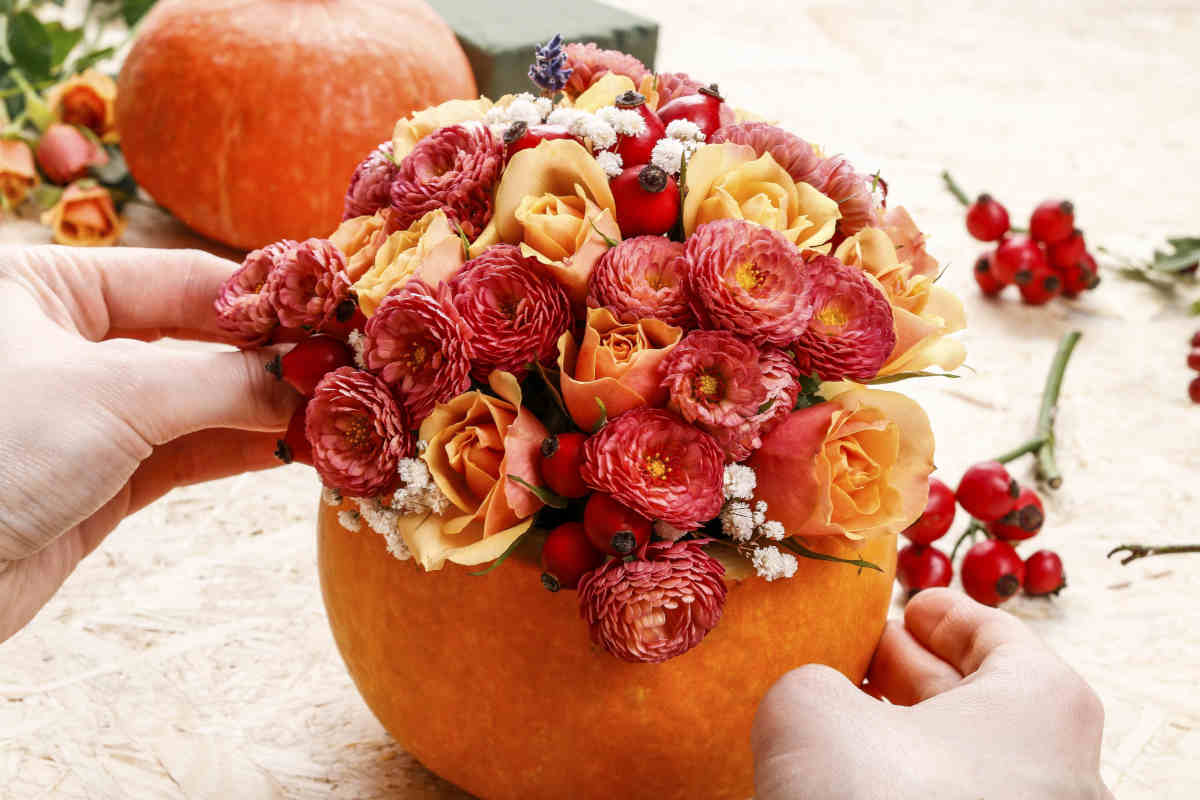 donna sistema fiori in un vaso ricavato nella zucca di halloween