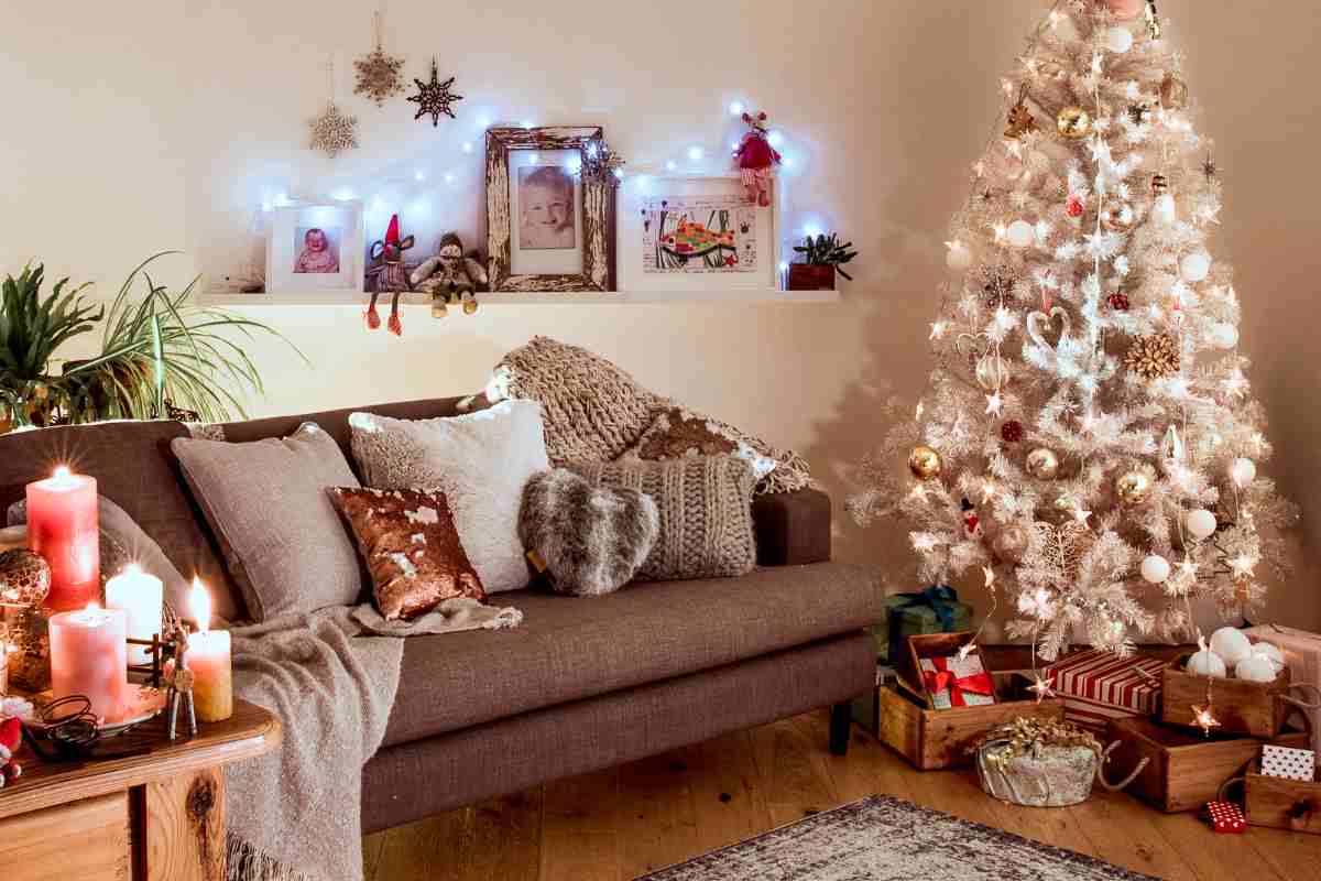 Albero di Natale vicino a divano in soggiorno con decorazioni natalizie in stile nordico
