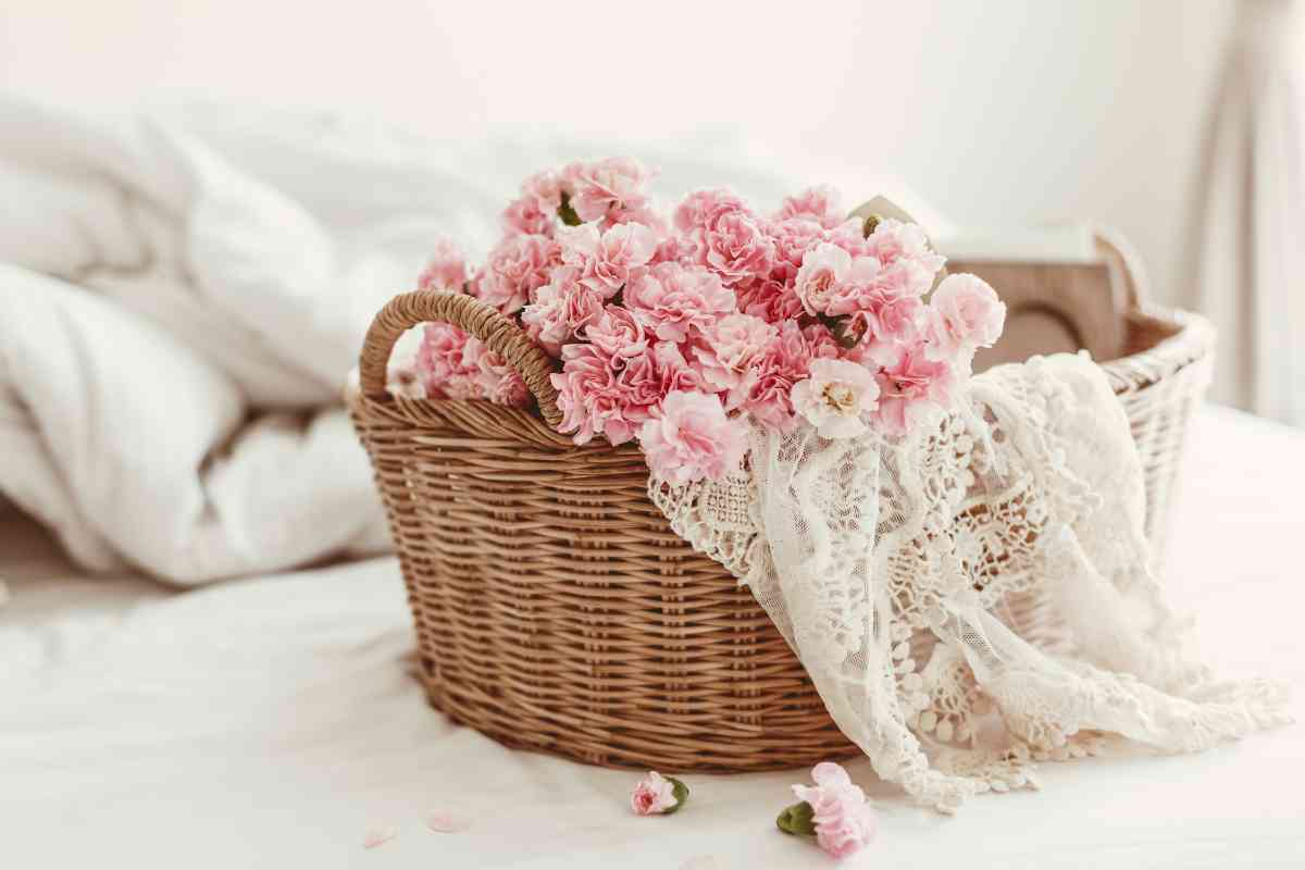 rose rosa e telo in pizzo in un cestino di vimini sul letto