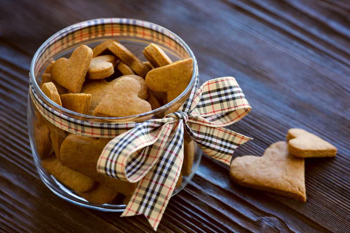 barattolo in vetro con biscotti a forma di cuore all'interno e fiocco a quadri beige e nero 