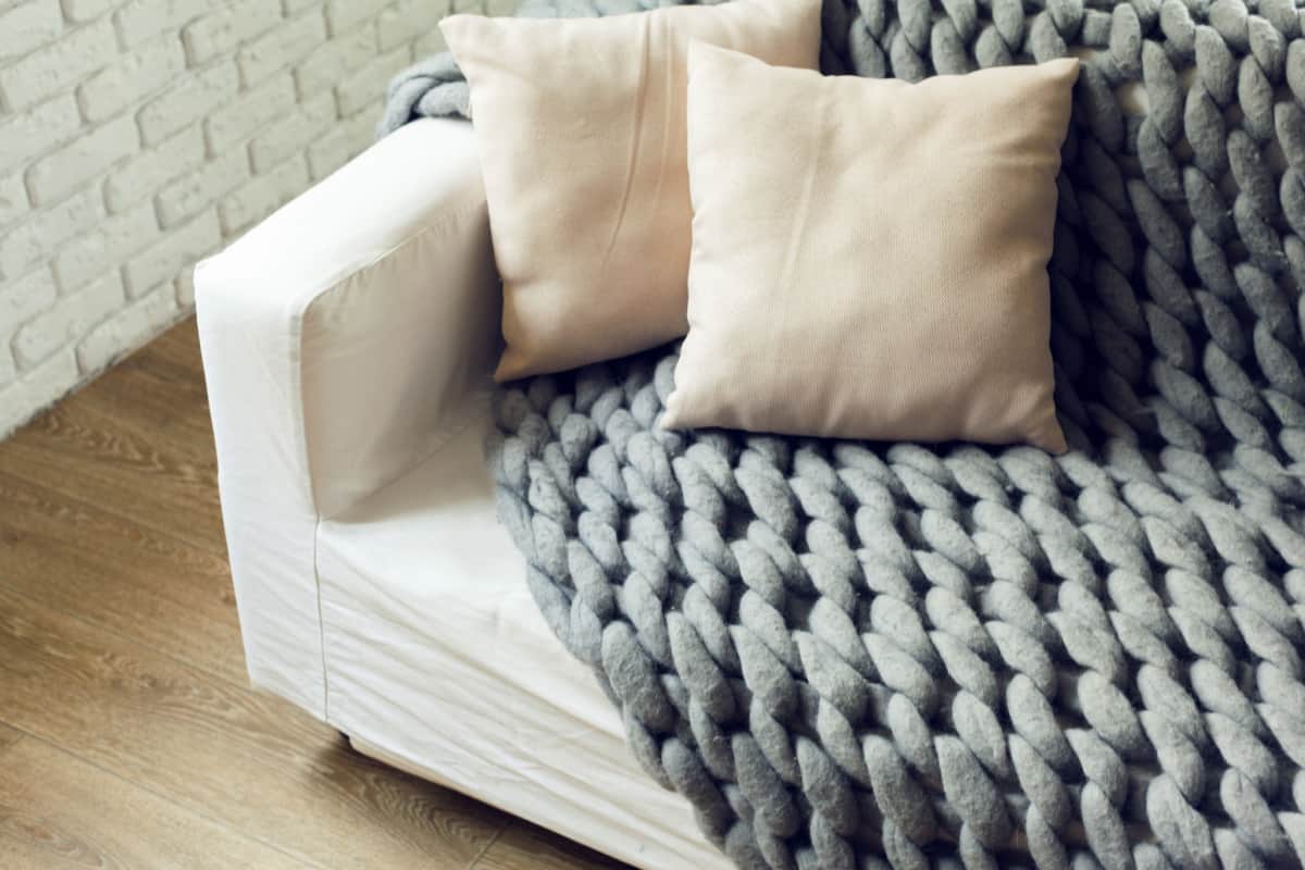 coperta di lana di colore grigio su un divano di colore bianco con due cuscini