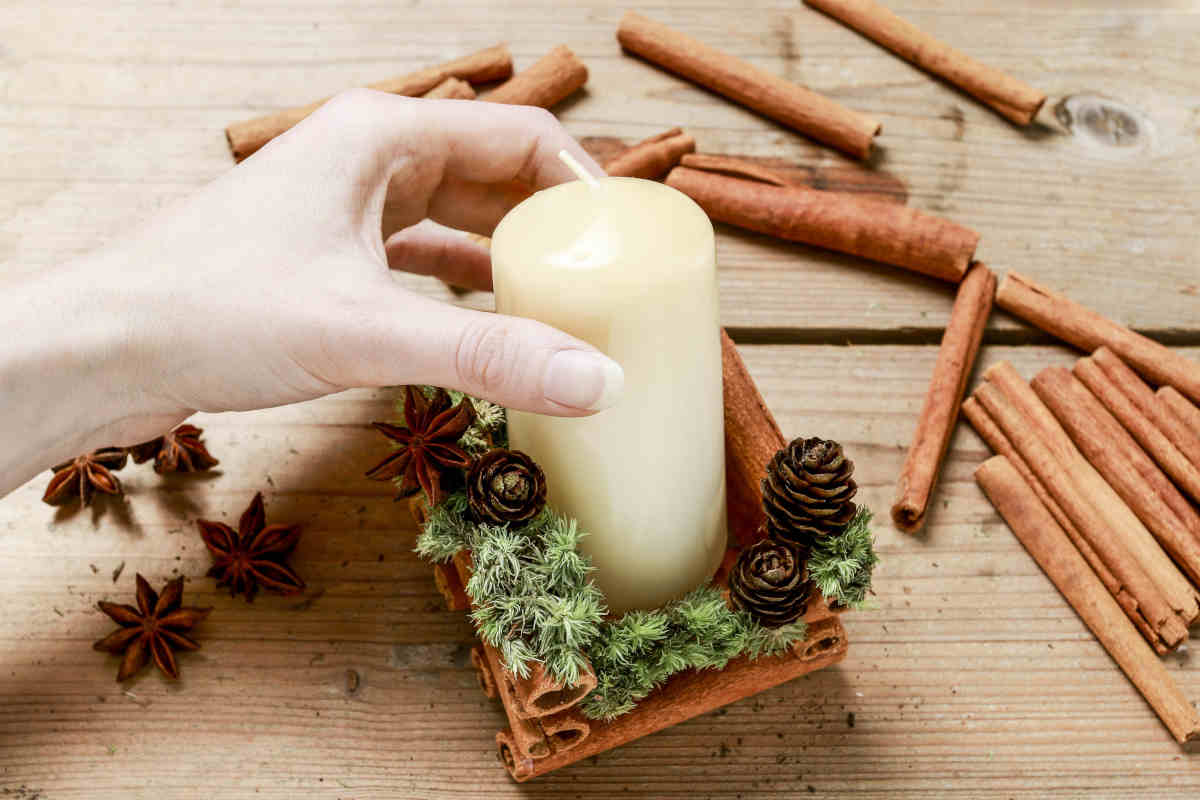 donna sistema una candela in un portacandele fai da te in legno e cannella