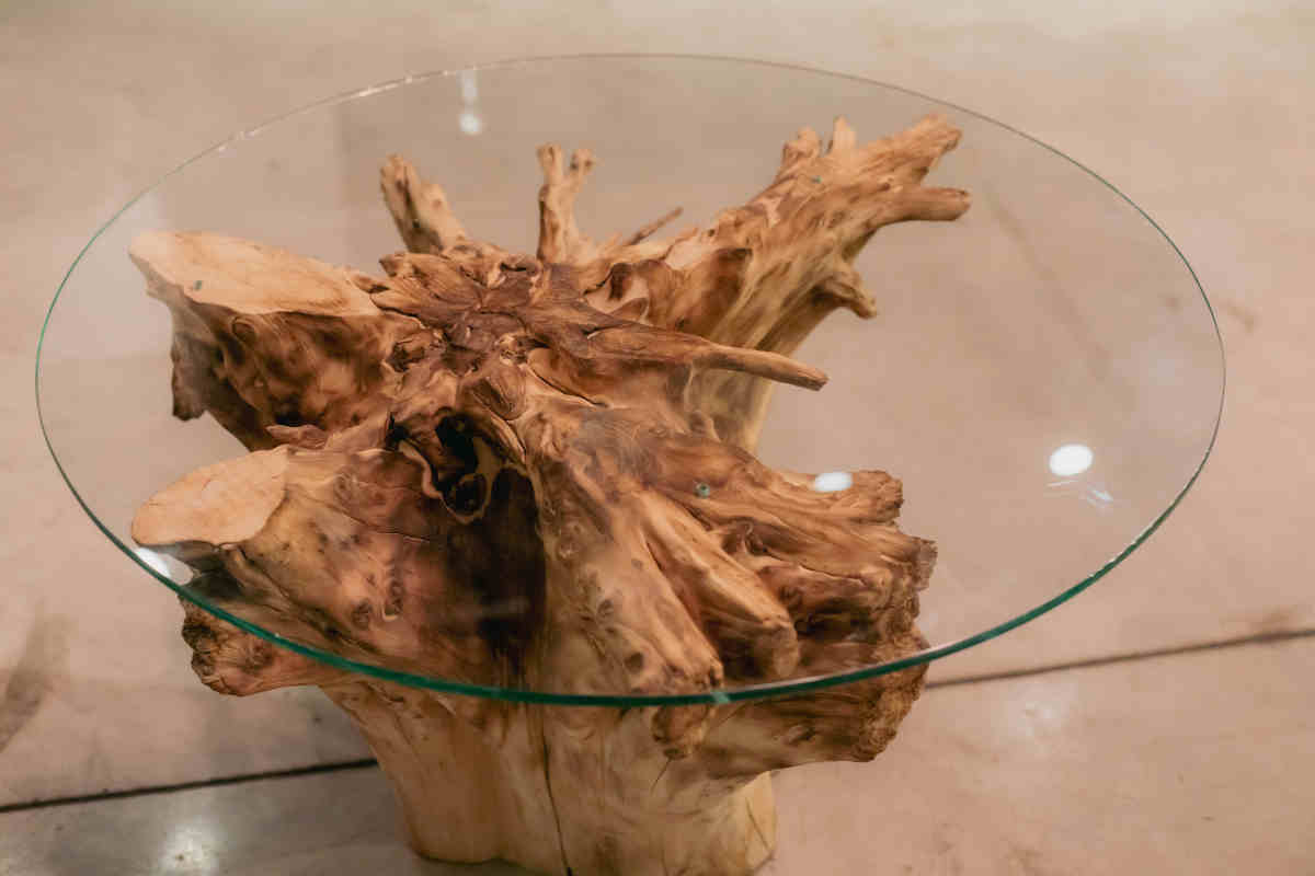 tavolo rotondo in vetro con struttura fatta di tronco di legno