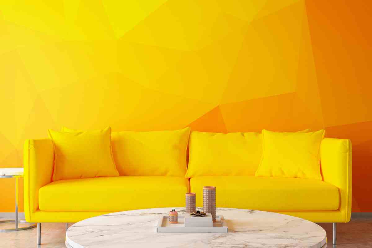 salotto con divano giallo e parete dipinta in varie tonalità vibranti