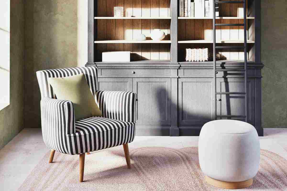 poltrona a righe davanti a libreria color tortora e pouf bianco