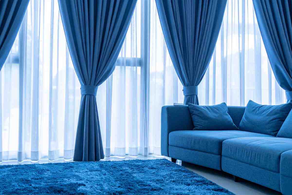 soggiorno con divano blu, tappeto a pelo lungo e tende dello stesso colore