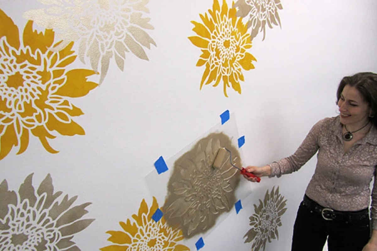 donna decora la parete con stencil e rullo