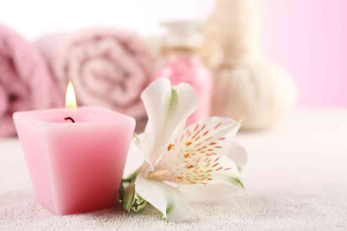 candela rosa e fiore con sullo sfondo asciugamani delle tonalità del rosa