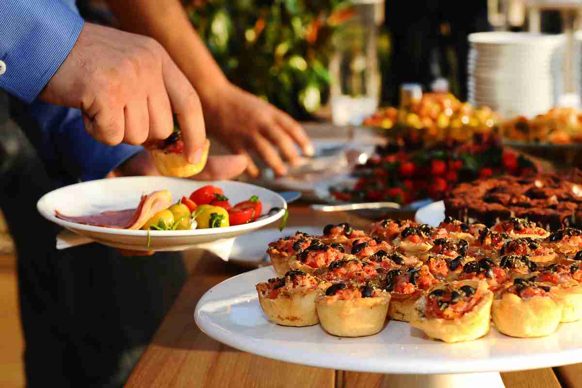 Uomo mette cibi nel piatto da un brunch a buffet