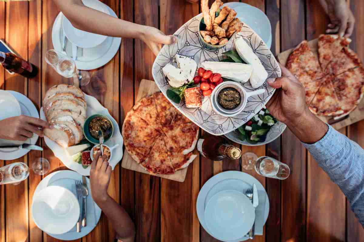 persone si passano il piatto seduti alla tavola da brunch vista dall'alto