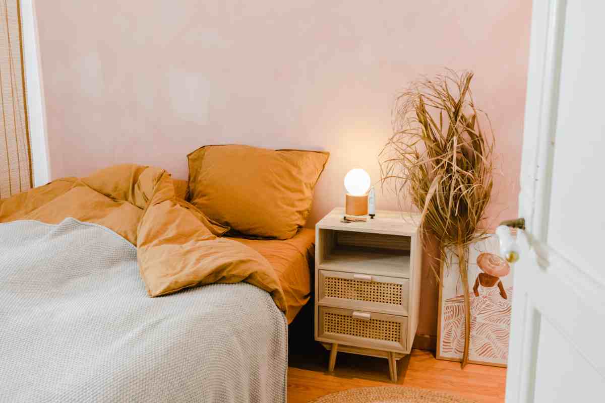Camera da letto scandinava con comodino in legno chiaro e letto senza testata