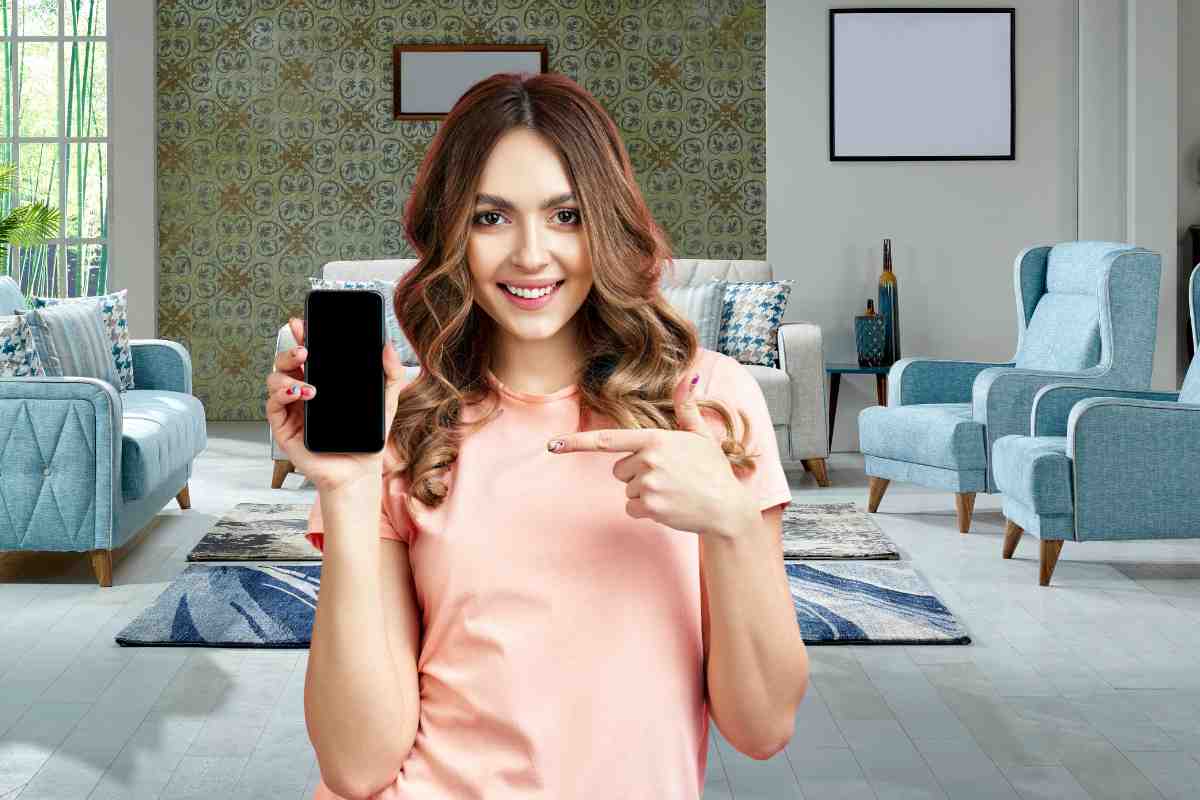 ragazza mostra smartphone con app per appassionati di design con sullo sfondo un soggiorno arredato nei toni del blu