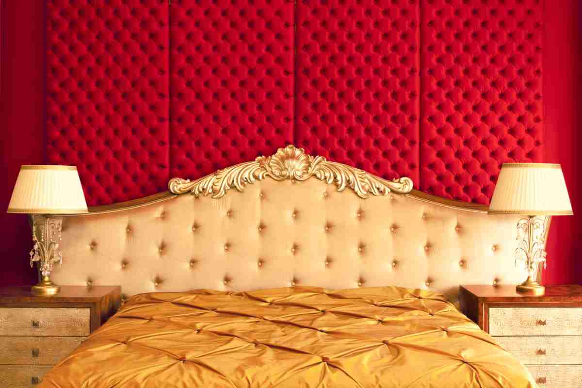 Camera da letto con parete rossa e letto con testiera oro