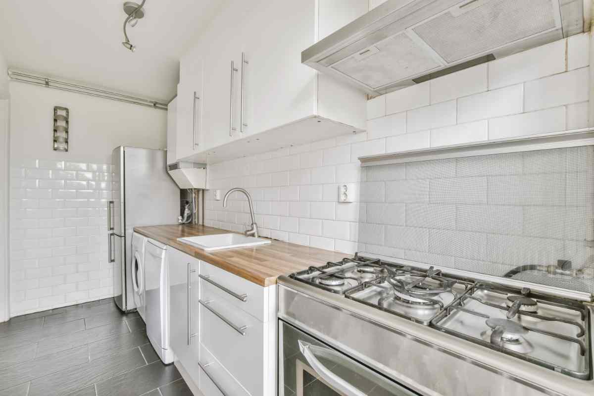 Cucina lunga e stretta con piano di lavoro in legno e lavatrice incassata