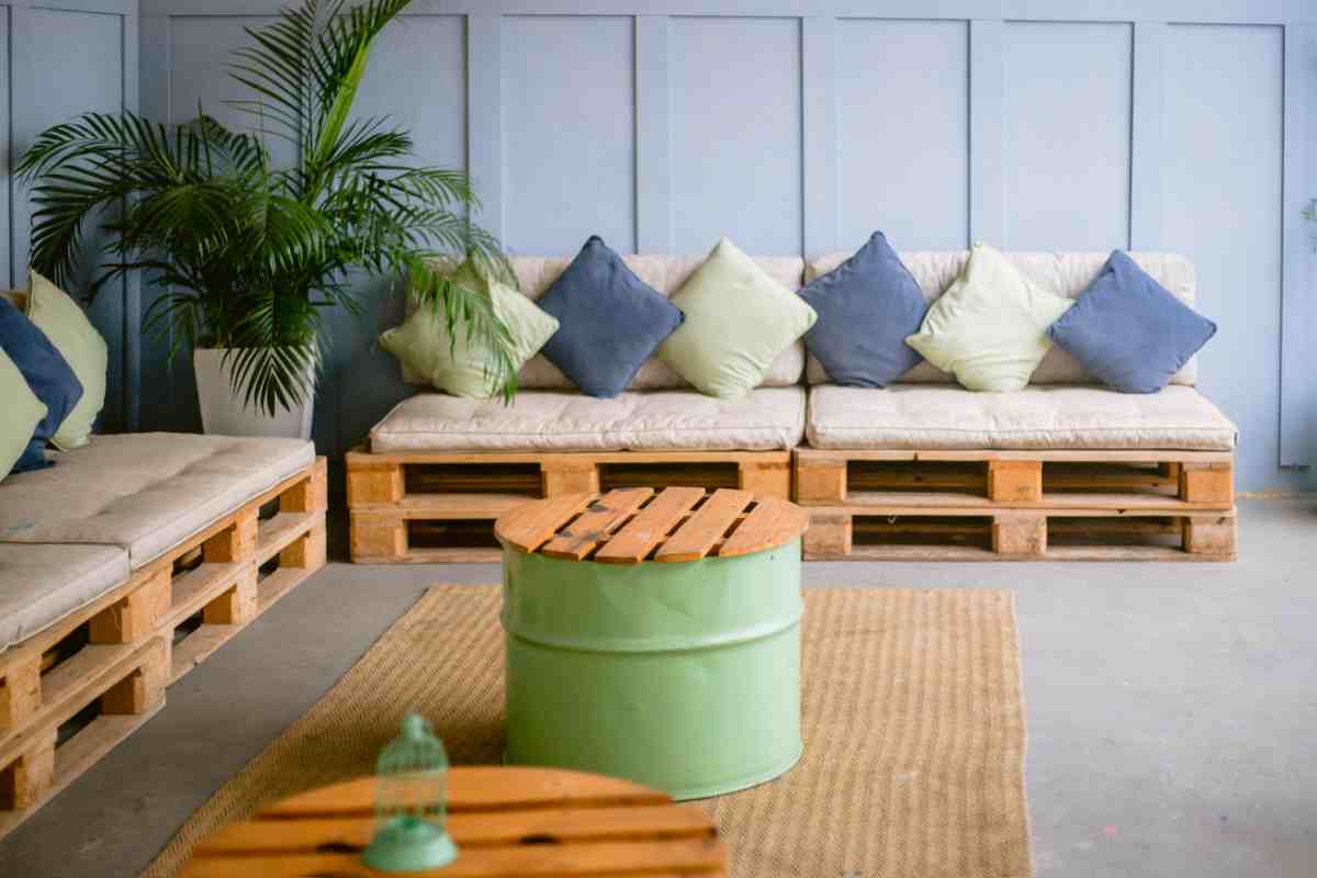 Divani con pallet posti in un terrazzo con tavolini ricavati da bidoni di metallo