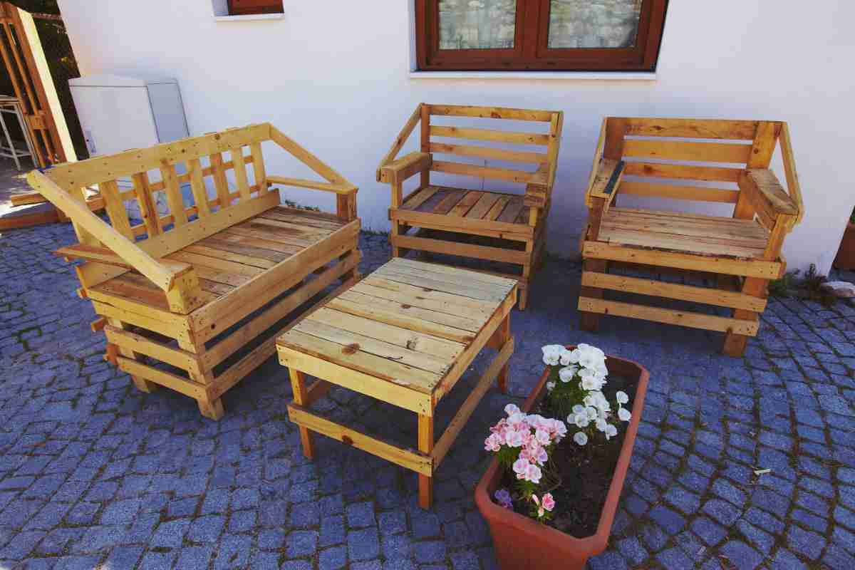 Salotto con i pallet in un terrazzo con vicino una fioriera