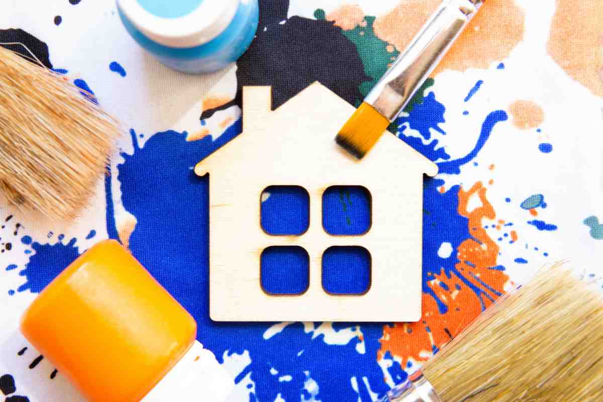 sagoma di casa con diversi tipi di pittura e pennelli
