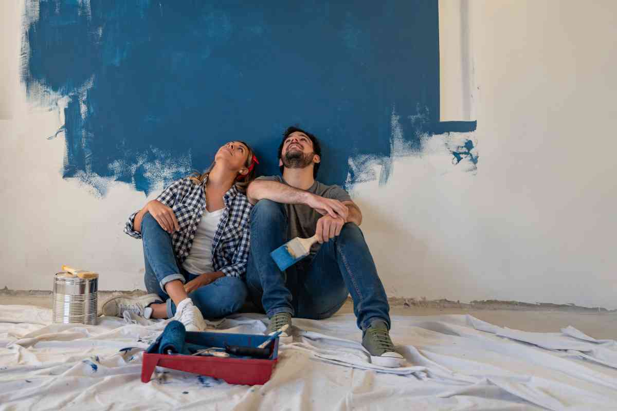 due ragazzi seduti davanti a una parete dipinta con una pittura di colore blu