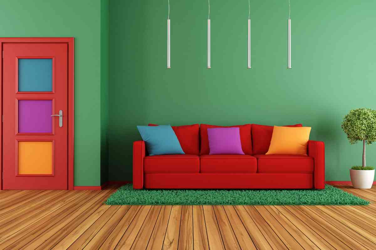 divano di colore rosso davanti a parete verde e pavimento in parquet
