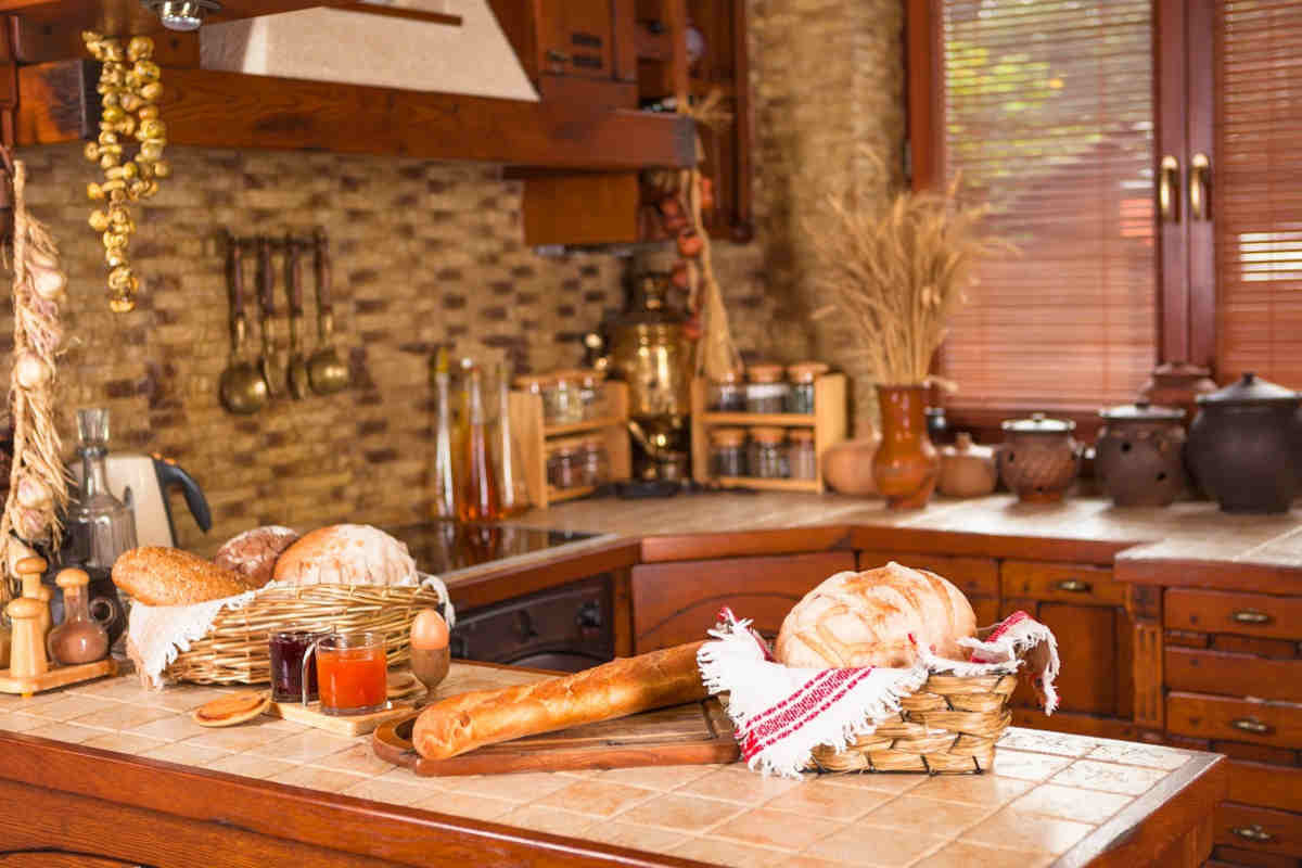 angolo cottura di una cucina in muratura classica con piastrelle e ante in legno