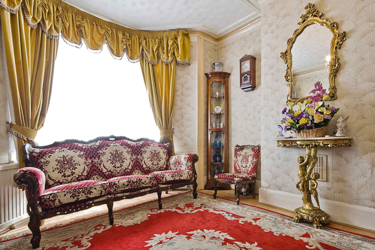 interno di un soggiorno con tappeti, tende e specchi arredato in stile vittoriano