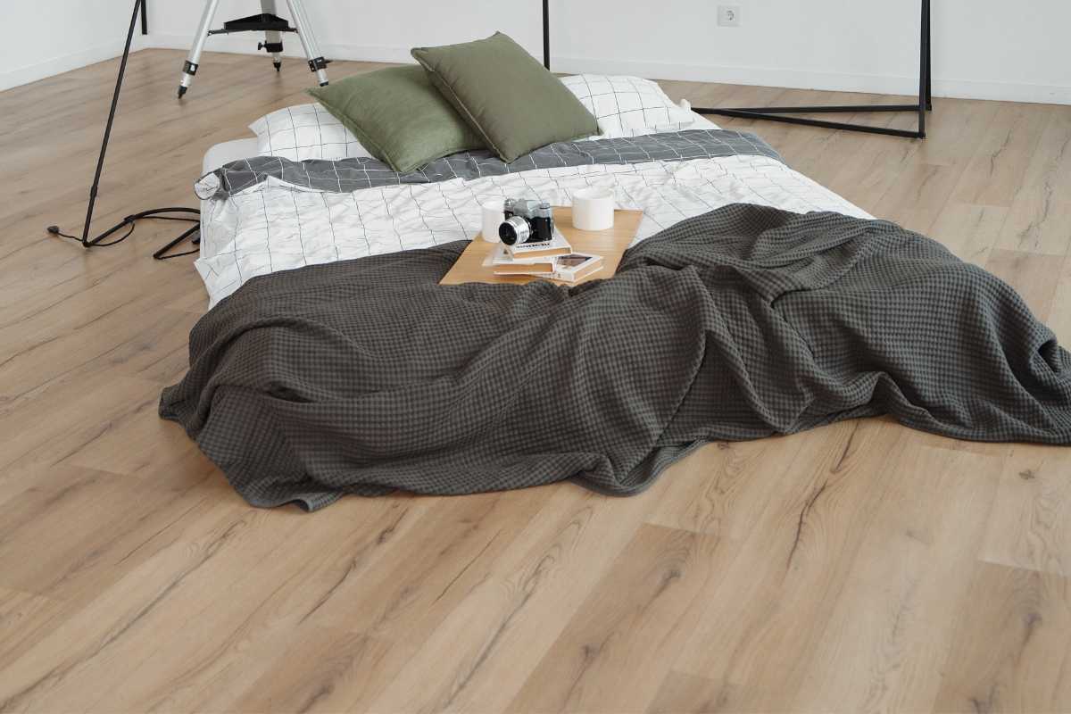 una camera da letto con pavimento rivestito in gres porcellanato effetto legno