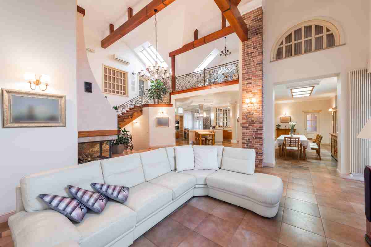soggiorno con divano angolare di colore bianco e parete decorata con pietre