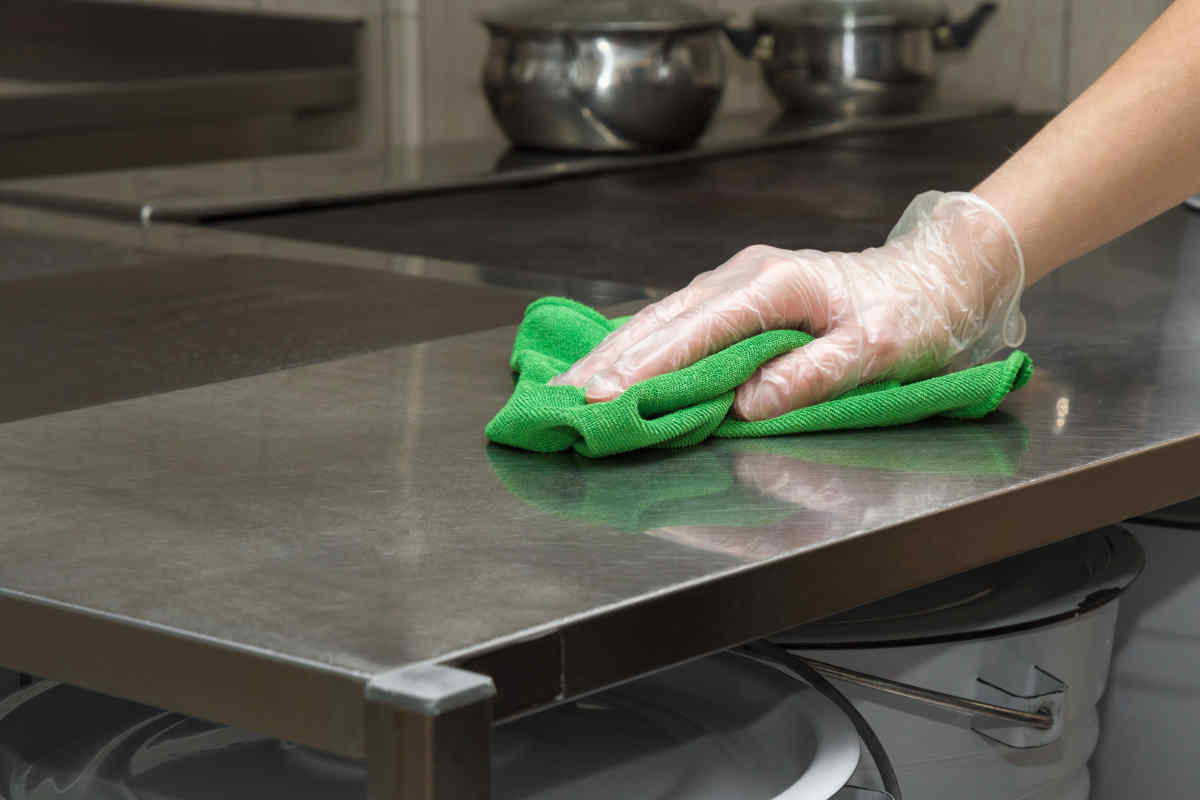donna pulisce il piano della cucina in acciaio con un panno morbido