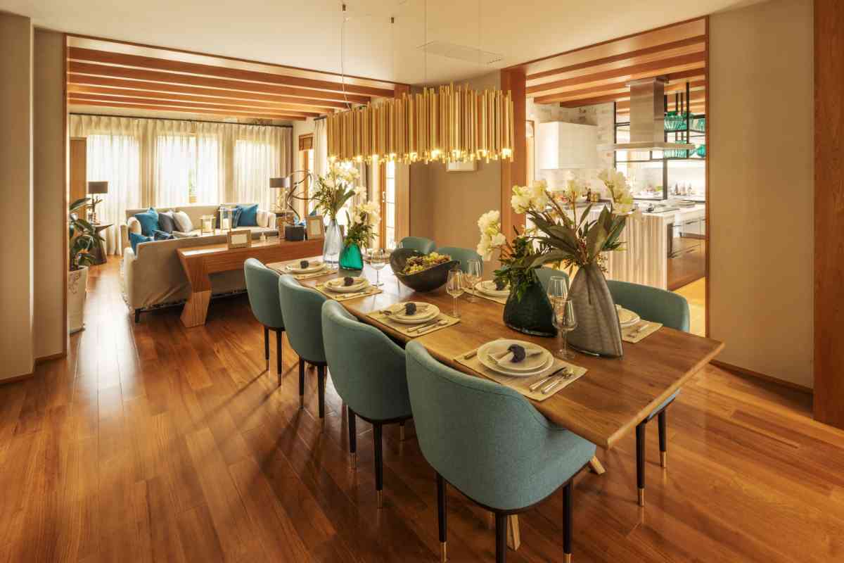 una sala da pranzo con tavola apparecchiata e illuminata con lampada a sospensione rettangolare in finitura oro