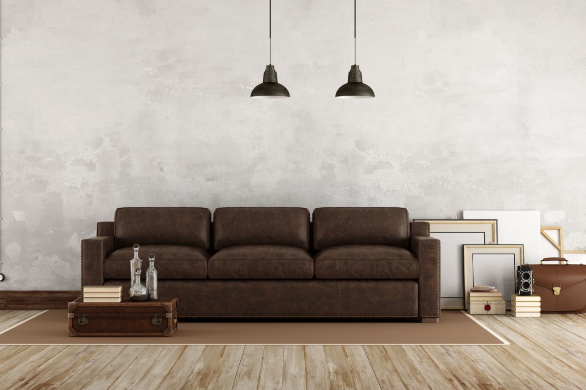 zona living con divano di colore marrone in tessuto ecopelle con parquet in legno e pareti bianche