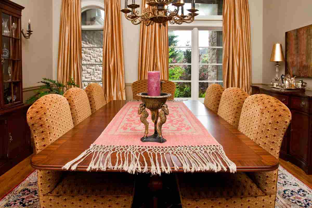 Sala da pranzo elegante con tavolo in legno, runner rosa e porta cero scolpito