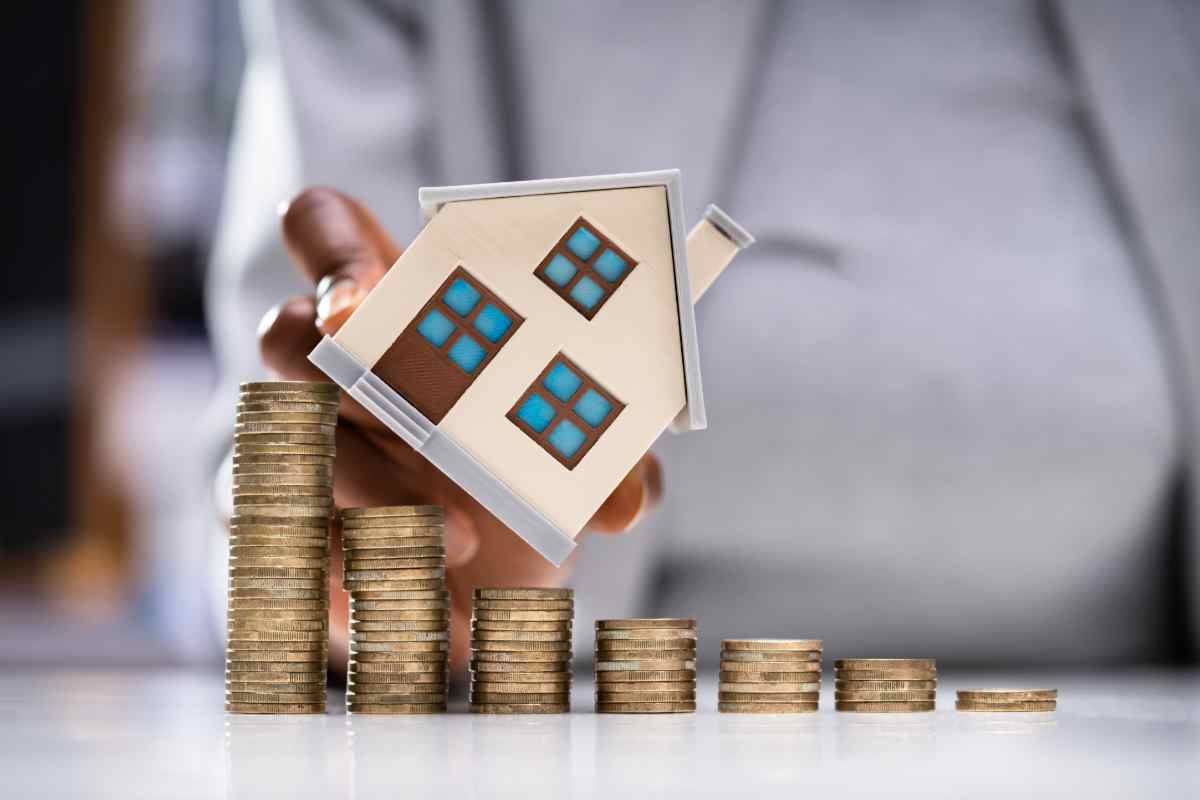 modellino di casa su pila di monete simbolo di come far aumentare il valore dell'immobile per la vendita e guadagnare molto di più