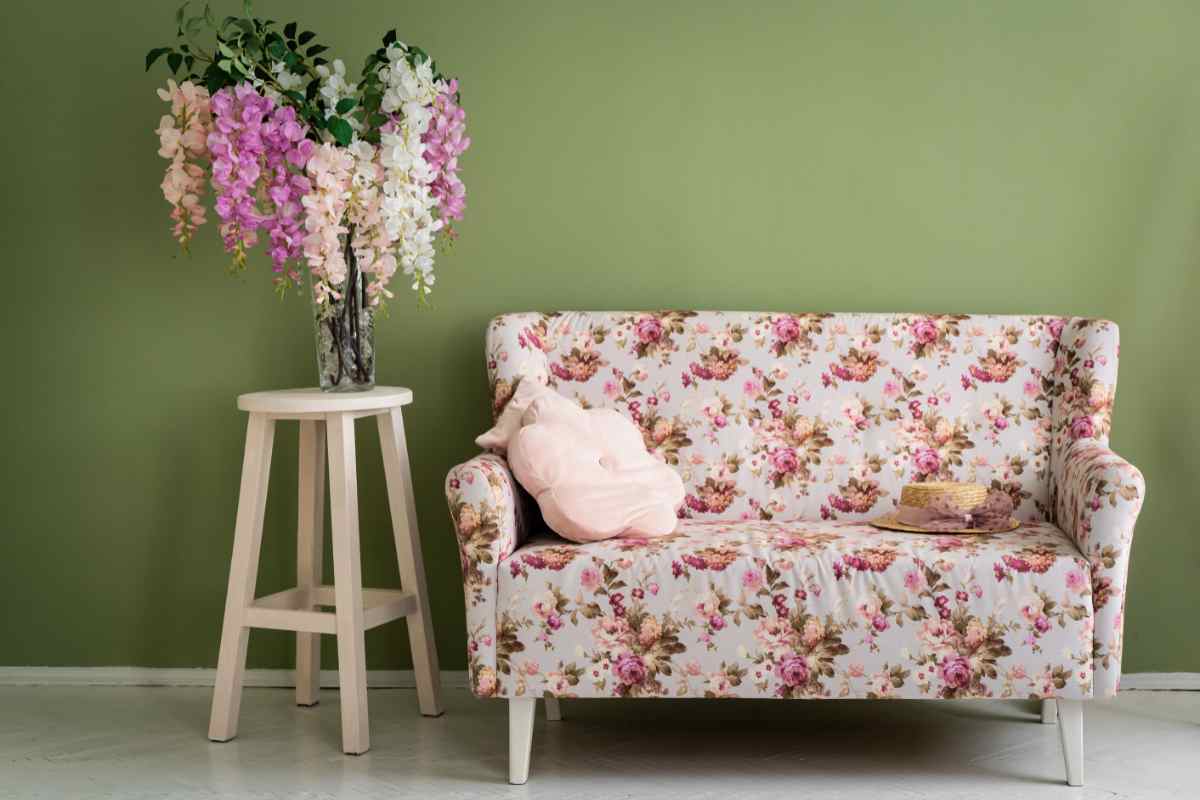 Un divano a fiori di tendenza vicino a un tavolino con un bouquet nel vaso
