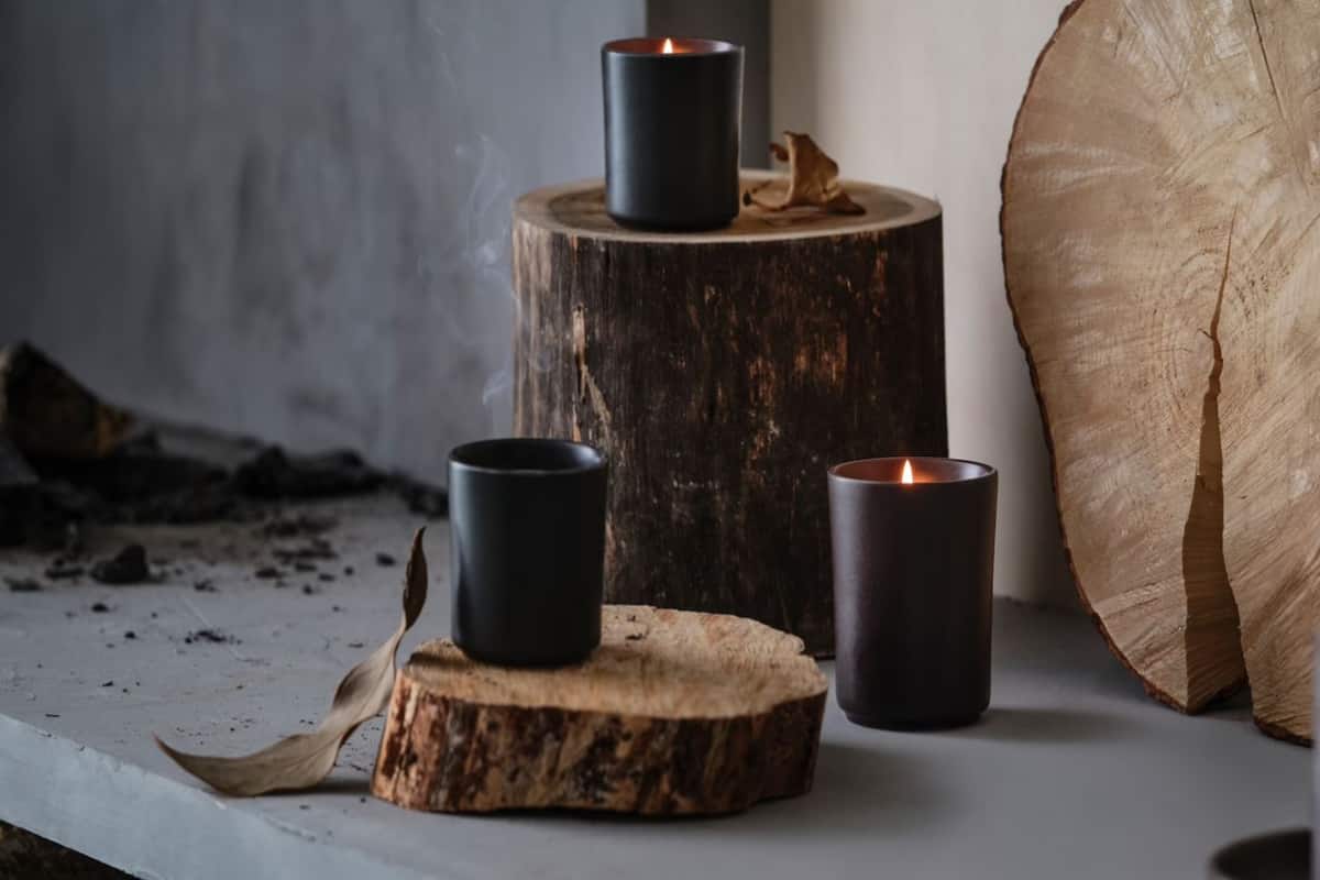 tre candele poggiate su dei ciocchi di legno 