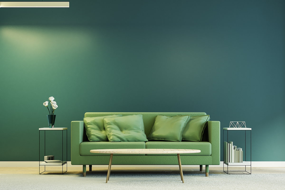 soggiorno con parete verde scuro e divano verde in pelle
