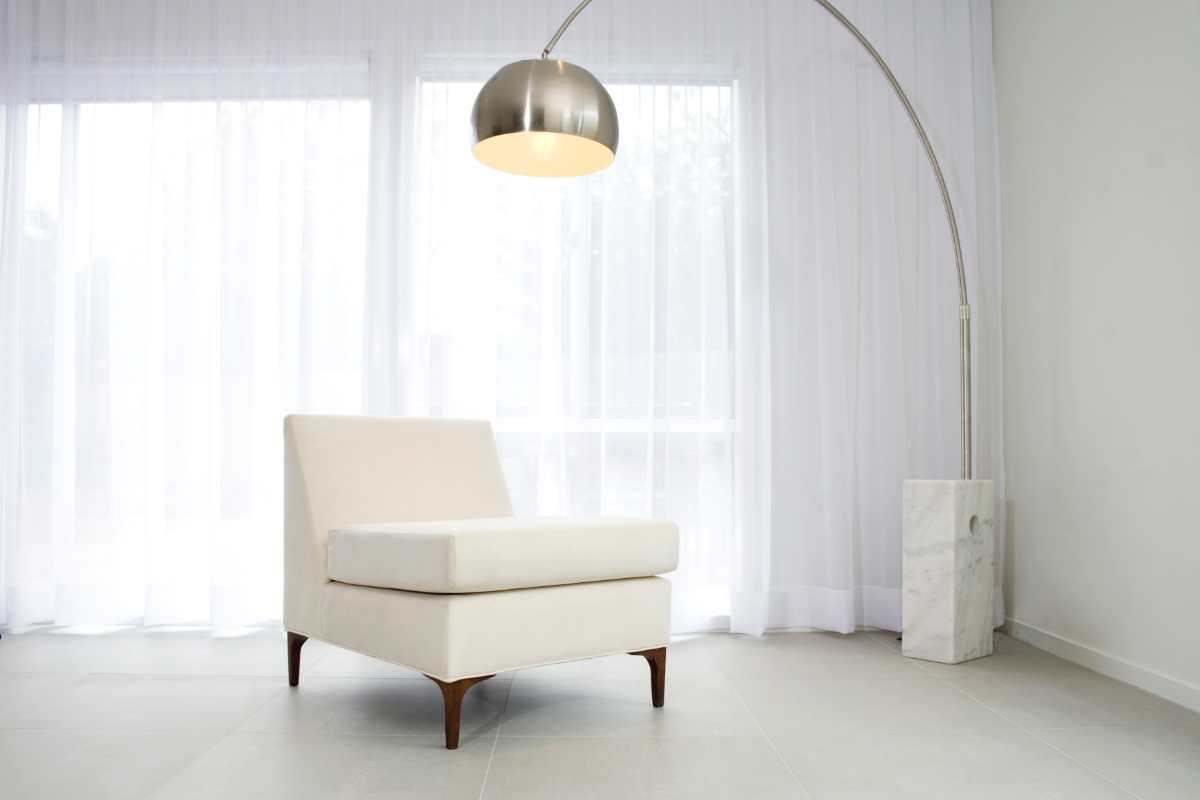 lampada arco di flos tra le migliori lampade di design di tutti i tempi che illumina una poltrona