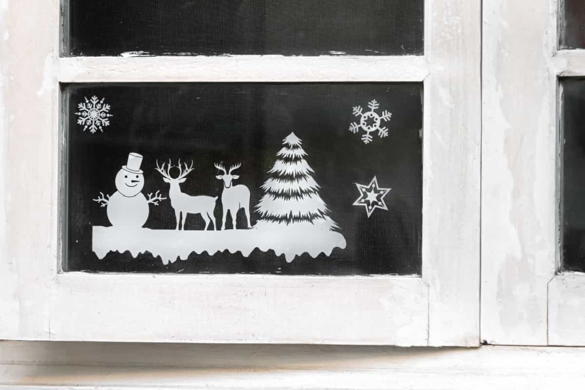 adesivi natalizi con fiocchi di neve, albero, renne, pupazzo di neve attaccati alle finestre