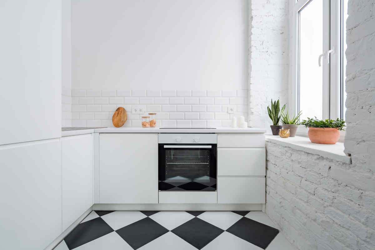 cucina bianca di piccole dimensioni con pavimento a scacchi bianco e nero