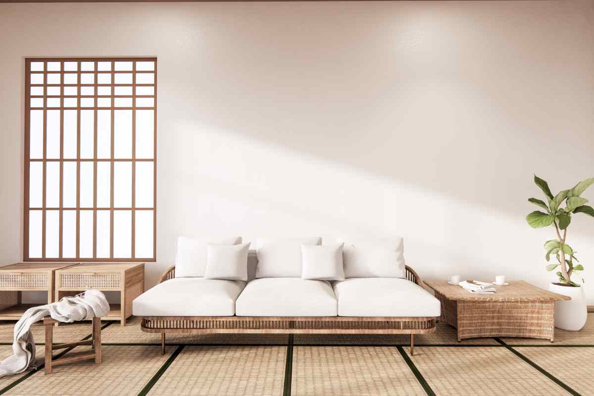 soggiorno arredato con mobili stile zen, divano basso con cuscini bianchi, tavolino in legno e piante