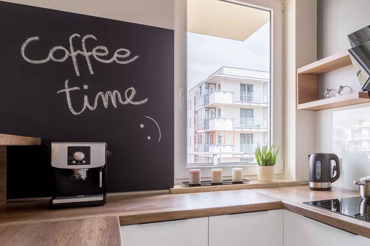 una cucina angolare con penisola con una delle pareti a effetto lavagna su cui è scritto coffee time